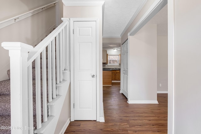 stairs with crown molding, a textured ceiling, baseboards, and wood finished floors