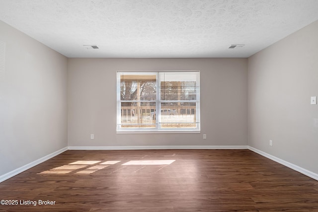 empty room featuring visible vents, baseboards, and wood finished floors