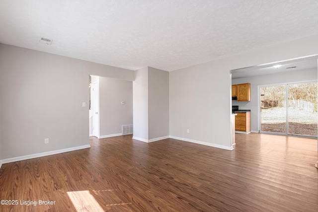 unfurnished living room with dark wood-style floors, baseboards, and visible vents