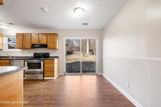 kitchen featuring stainless steel appliances, visible vents, under cabinet range hood, and wood finished floors