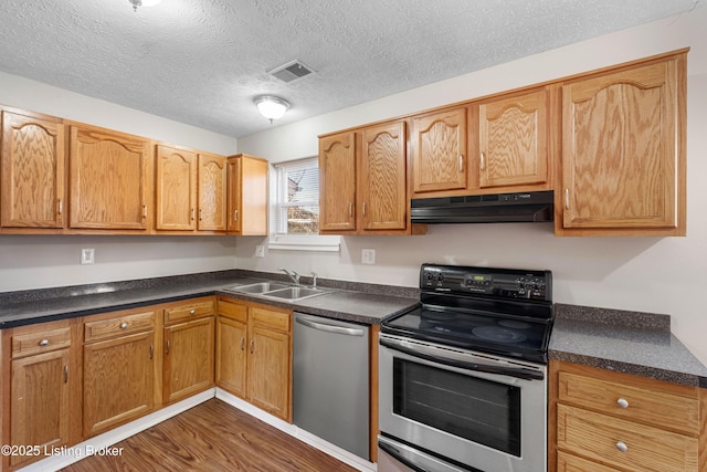 kitchen with visible vents, dark wood-style floors, stainless steel appliances, under cabinet range hood, and a sink