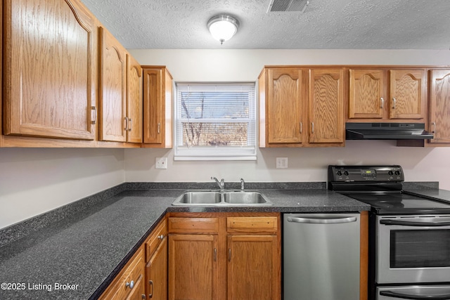 kitchen featuring visible vents, dark countertops, appliances with stainless steel finishes, under cabinet range hood, and a sink