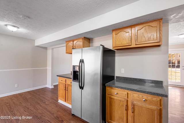 kitchen with a textured ceiling, dark wood-style flooring, dark countertops, and stainless steel fridge with ice dispenser