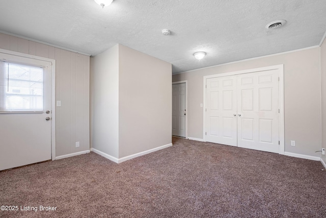 interior space featuring baseboards, visible vents, crown molding, a textured ceiling, and carpet floors