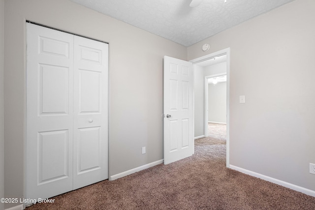 unfurnished bedroom with baseboards, ceiling fan, a textured ceiling, carpet floors, and a closet