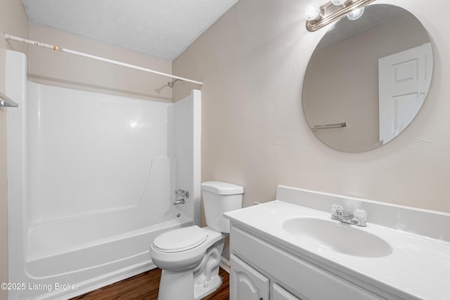 full bath with a textured ceiling, toilet, wood finished floors, vanity, and shower / washtub combination