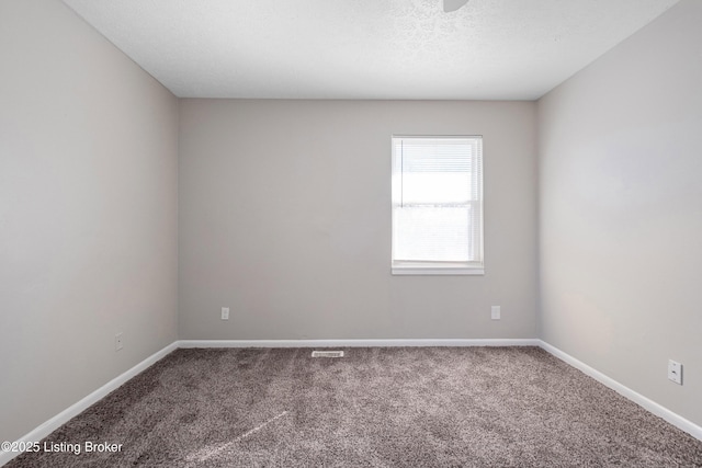 spare room featuring a textured ceiling, carpet, visible vents, and baseboards