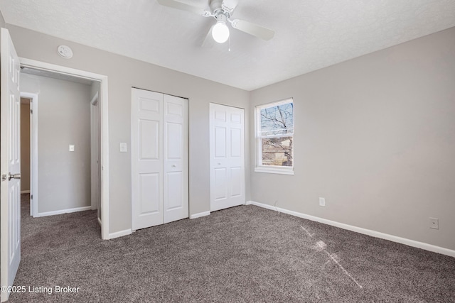 unfurnished bedroom featuring carpet, multiple closets, ceiling fan, a textured ceiling, and baseboards