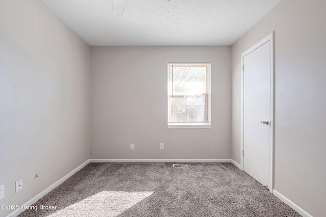 unfurnished room featuring carpet flooring, a textured ceiling, and baseboards