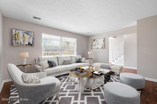 living area featuring baseboards, visible vents, stairway, wood finished floors, and a textured ceiling