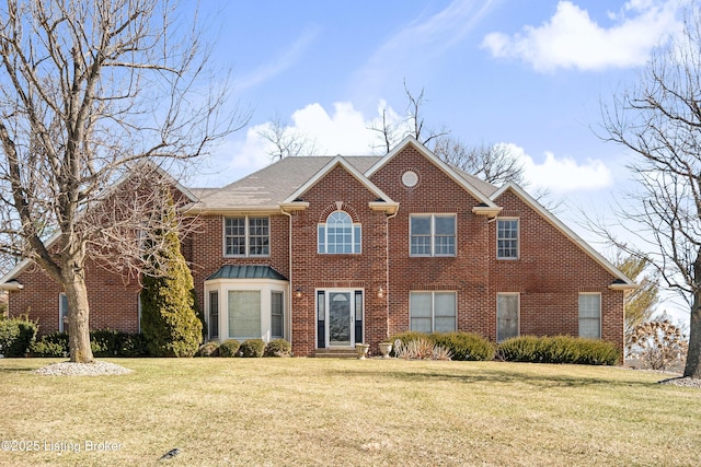 view of front of house with a front lawn, a shingled roof, and brick siding