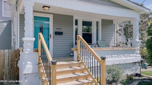 entrance to property featuring covered porch and fence