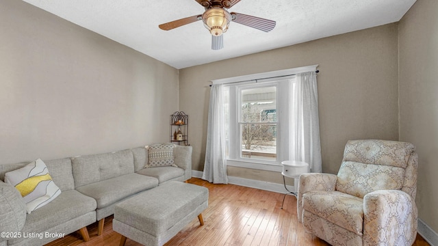 living room featuring ceiling fan, wood-type flooring, and baseboards