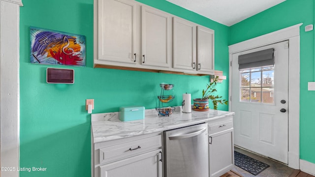 kitchen with stainless steel dishwasher, light stone counters, and white cabinets