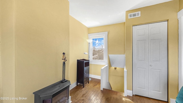 interior space with a closet, wood-type flooring, visible vents, and baseboards