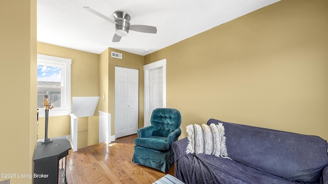 living room with ceiling fan, wood finished floors, and visible vents