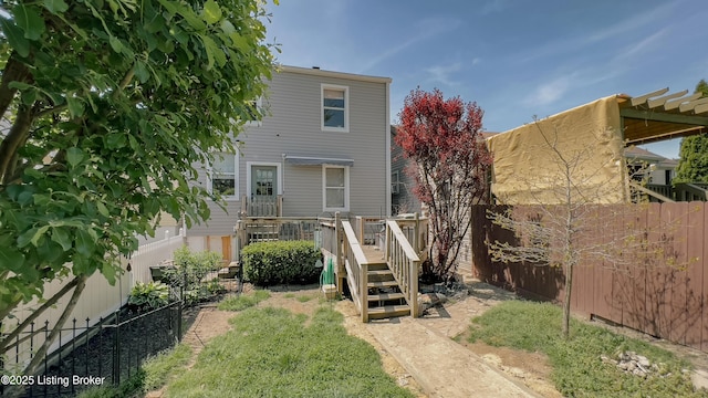 rear view of house with a fenced backyard and a deck