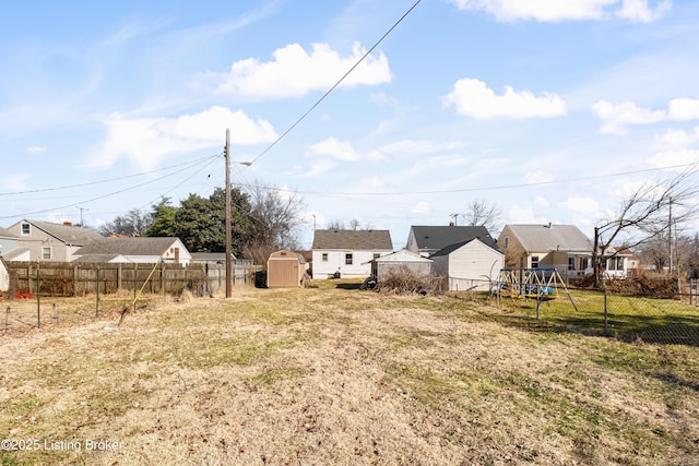 view of yard featuring a residential view, fence, an outdoor structure, a shed, and a playground