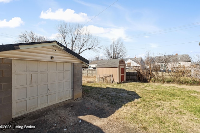 detached garage with a storage shed and fence