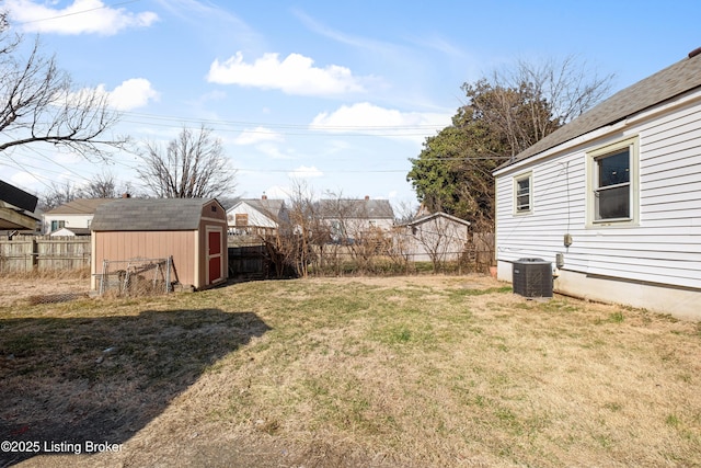 view of yard with a fenced backyard, a storage unit, cooling unit, and an outbuilding