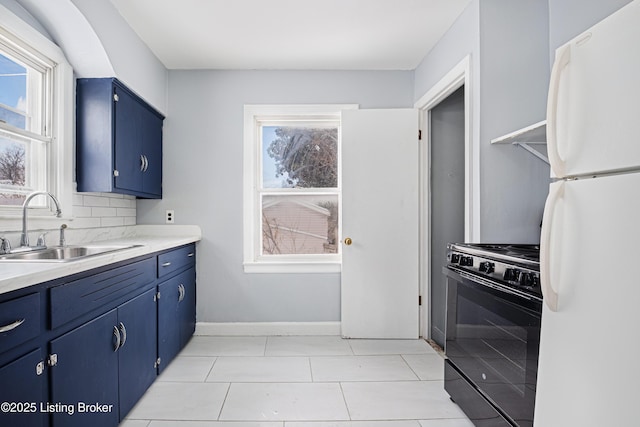 kitchen featuring freestanding refrigerator, light countertops, black gas stove, and a sink