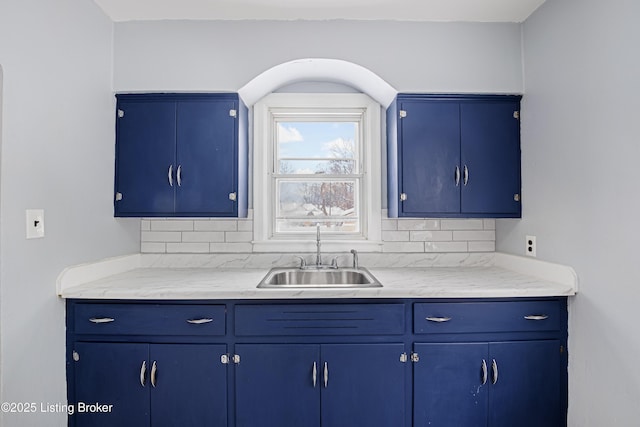 kitchen featuring blue cabinets, backsplash, and a sink