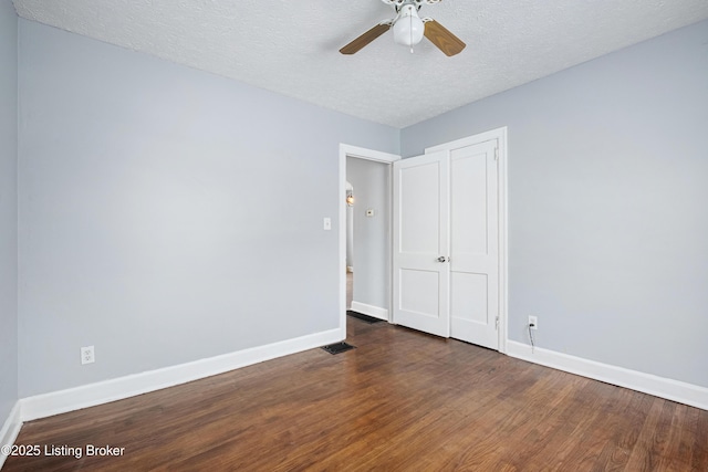 unfurnished bedroom featuring a textured ceiling, dark wood-type flooring, a ceiling fan, baseboards, and a closet