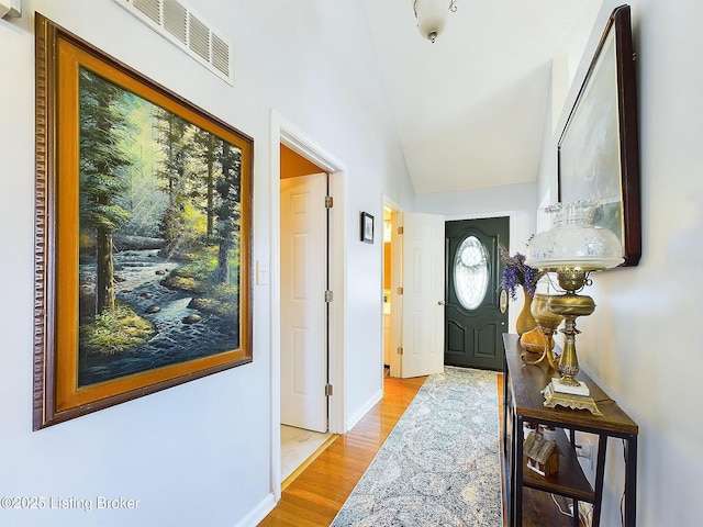 entryway with lofted ceiling, baseboards, visible vents, and wood finished floors