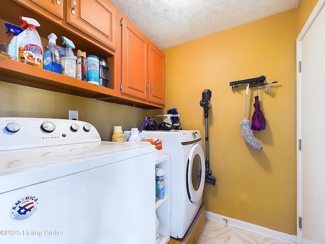 clothes washing area featuring a textured ceiling, washer and clothes dryer, cabinet space, and baseboards