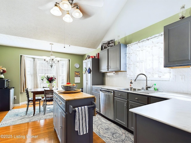 kitchen with lofted ceiling, dishwasher, backsplash, and a sink