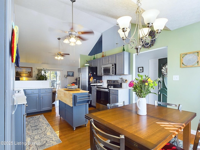 kitchen featuring a kitchen island, wood finished floors, vaulted ceiling, stainless steel appliances, and wooden counters