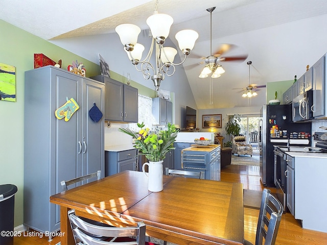 dining area with lofted ceiling, ceiling fan with notable chandelier, and light wood-style flooring