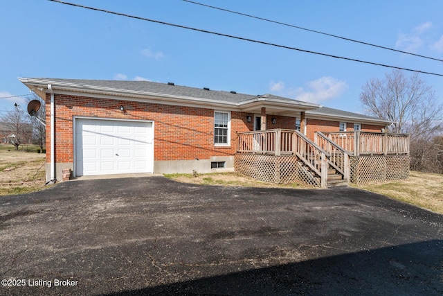 ranch-style home featuring an attached garage, driveway, a deck, and brick siding