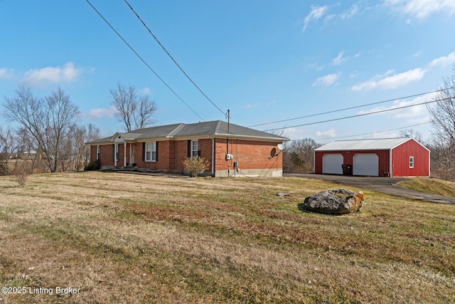 view of front of property featuring a front lawn, brick siding, a detached garage, and an outdoor structure