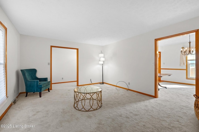 sitting room featuring carpet floors, baseboards, and a notable chandelier