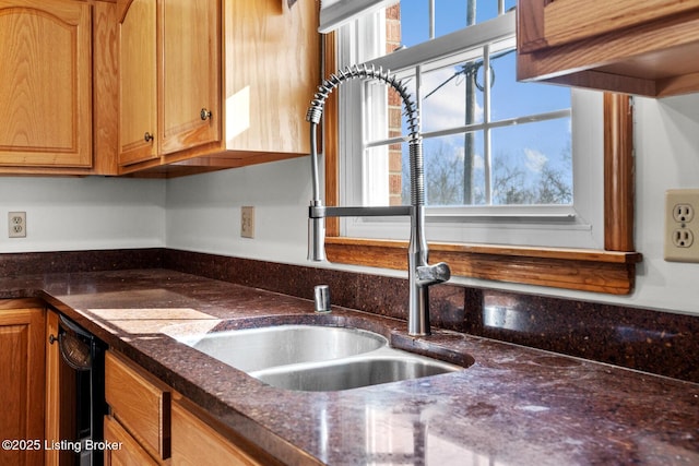 kitchen with dark stone counters, a sink, and dishwasher