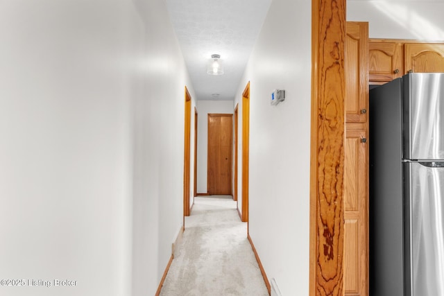 hallway with light colored carpet and baseboards