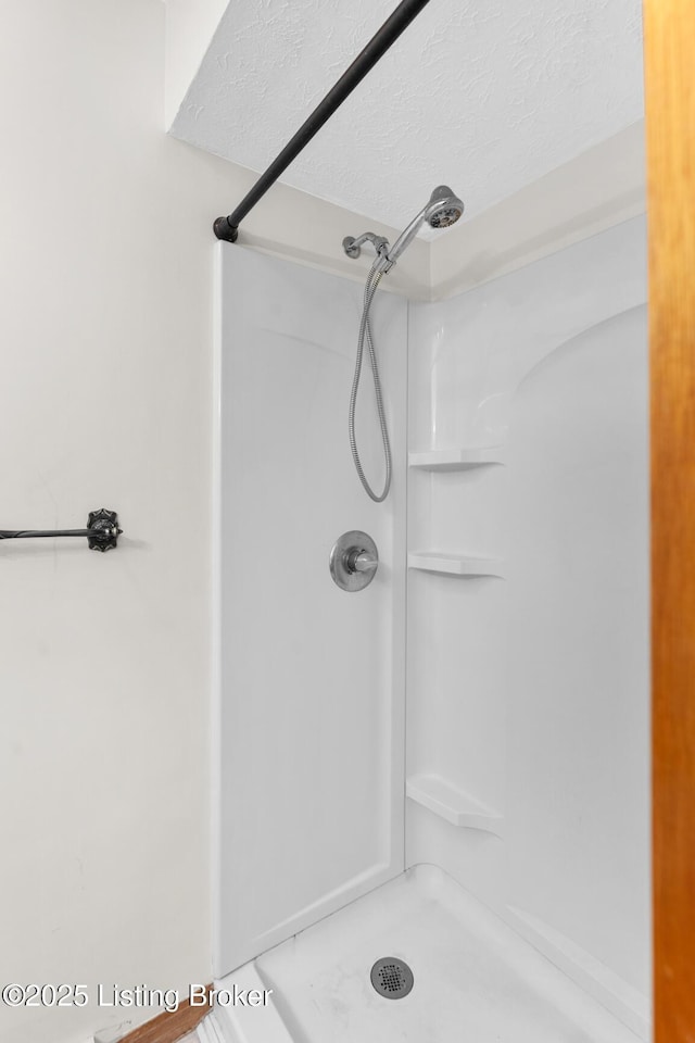 bathroom with a textured ceiling and a stall shower