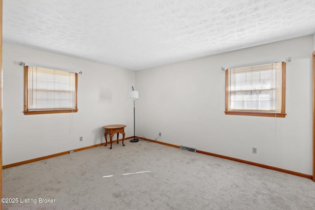 unfurnished room featuring carpet, a textured ceiling, visible vents, and baseboards