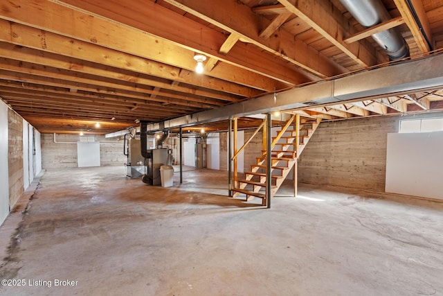 basement featuring stairs, water heater, and heating unit