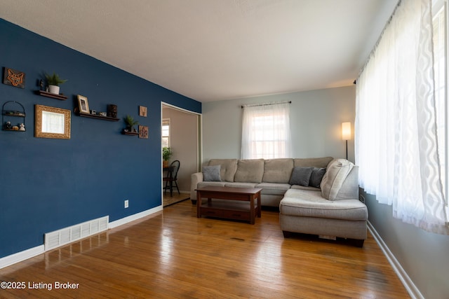 living area with visible vents, baseboards, and hardwood / wood-style flooring