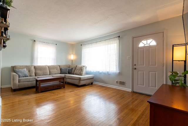 living area featuring light wood-style floors, visible vents, and a wealth of natural light