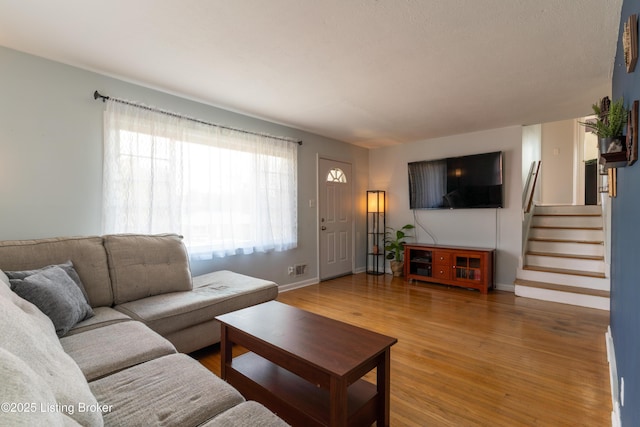 living room featuring stairway, baseboards, and wood finished floors