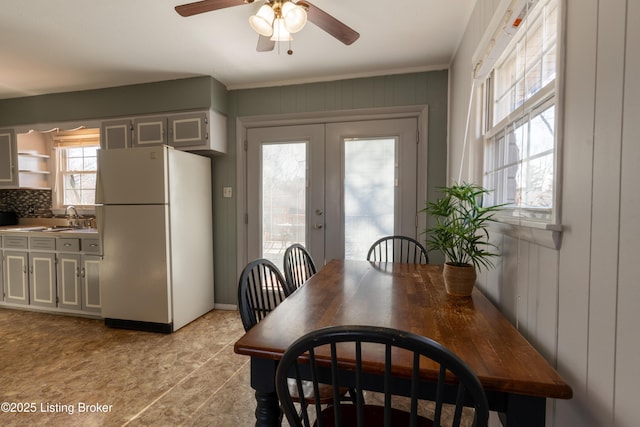 dining space featuring french doors, wood walls, and a ceiling fan