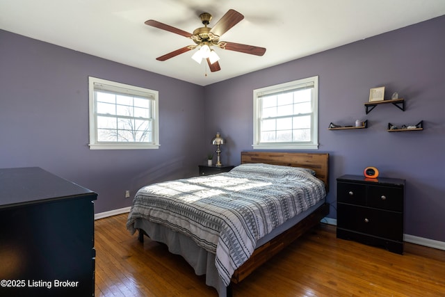 bedroom featuring a ceiling fan, multiple windows, baseboards, and dark wood-type flooring