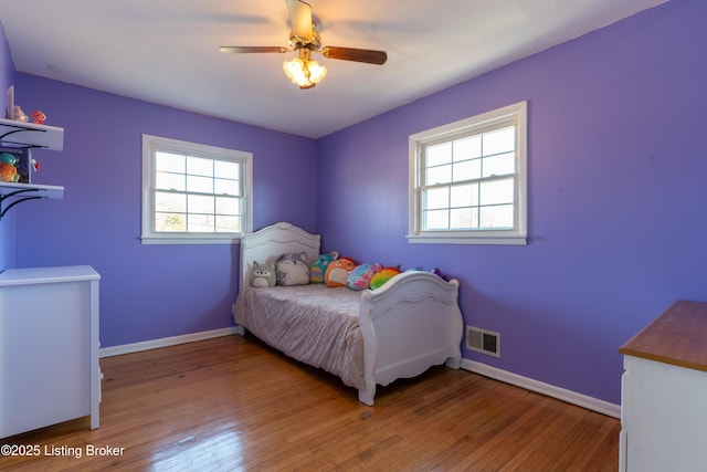 bedroom with multiple windows, visible vents, and hardwood / wood-style floors