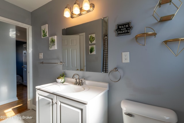 bathroom featuring baseboards, vanity, and toilet