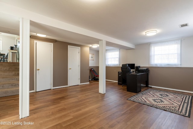 office space with baseboards, visible vents, and wood finished floors