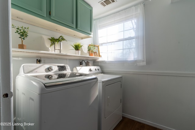 laundry area with a wainscoted wall, visible vents, washing machine and dryer, and cabinet space