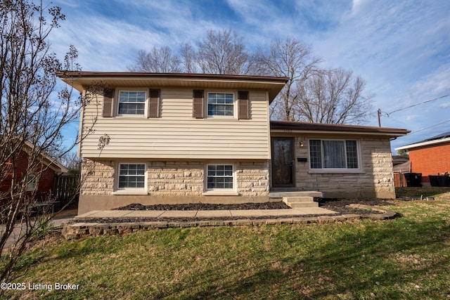 tri-level home featuring stone siding and a front lawn